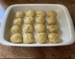 Step <p>Dividir la masa en 16 bolas de unos 70gr. cada una e ir colocando en la fuente,puedes pincelarla con aceite ó untarla con mantequilla,separadas entre sí.Tapamos con film transparente y dejar levar un segundo fermentado.45 mint.</p> illustration