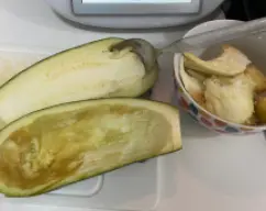 Step <p>Ponemos en el vaso la cebolla, el ajo y el aceite y troceamos 5 segundos a velocidad 4. Sofreímos8 minutos, 120ºC, velocidad 1. Mientras tanto, cortamos las berenjenas por la mitad y las vaciamos quitando y reservando el interior con ayuda de una cuchara. </p> illustration